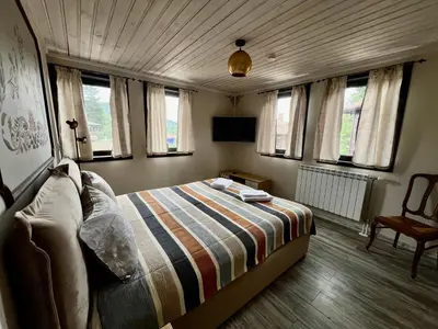 a bedroom with a bed in a room with windows at Китанова къща in Koprivshtitsa