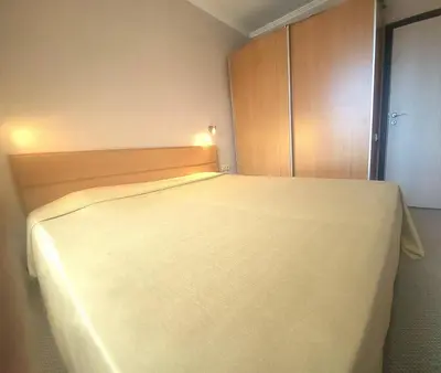 a bedroom with a white bed with a wooden cabinet at Апартамент А101 хотел Снежанка in Pamporovo