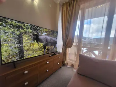 a living room with a large screen tv and a couch at Апартамент А101 хотел Снежанка in Pamporovo