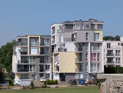 a tall apartment building with cars parked in front of it at Апартамент - Студио Престиж 2 in Hisarya