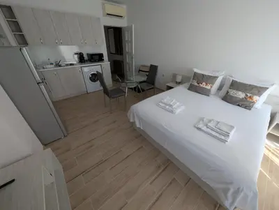 a bedroom with a large white bed and a kitchen at Апартамент - Студио Престиж 2 in Hisarya