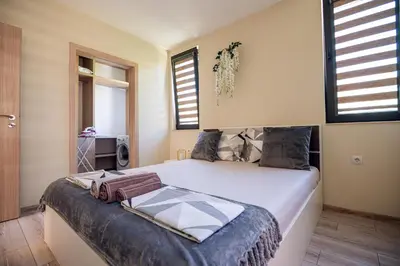 a bedroom with a large bed in a room with windows at ДиНати in Plovdiv