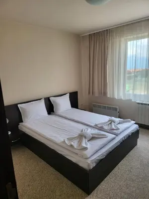 a bedroom with a bed with white sheets and a window at Bansko Royal towers Ski Lift Area in Bansko
