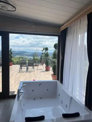 a bath tub in front of a large window at SAFI FOREST village in Dospat
