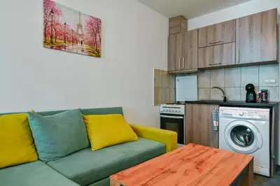 a living room with a green couch and a kitchen at Studio 19 in Sofia