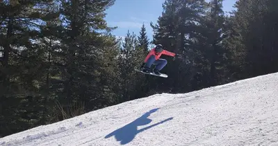 a person riding a snowboard down a snow covered slope at apartment Serenity, Bansko in Bansko