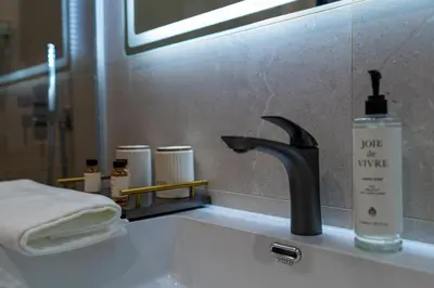 a bathroom sink with a black faucet and a mirror at Aurora Sofia in Sofia