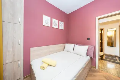 a small bedroom with a white bed and pink walls at Home Library in Sofia