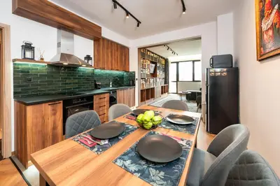 a kitchen with a wooden table with chairs and a refrigerator at Home Library in Sofia