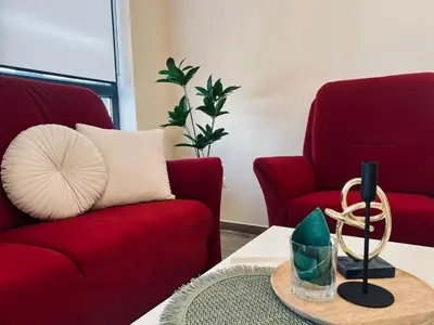 a living room with two red chairs and a table at Cherry Apartment with 2 bedrooms in Sofia