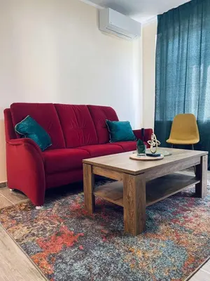 a living room with a red couch and a coffee table at Strаwberry Apartment in Sofia
