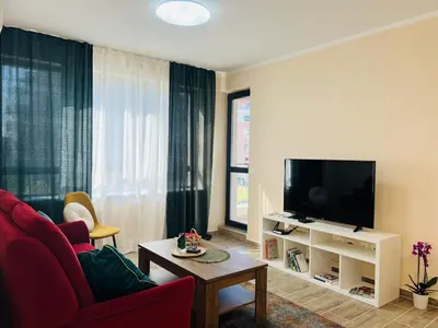 a living room with a red couch and a flat screen tv at Strаwberry Apartment in Sofia