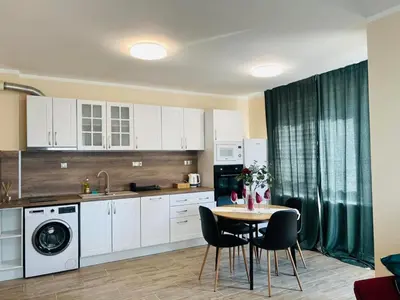 a kitchen with white cabinets and a table and chairs at Strаwberry Apartment in Sofia