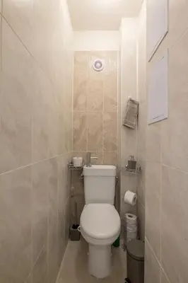 a bathroom with a toilet and a tiled wall at Stay and Play - Foosball and Comfort in Sofia