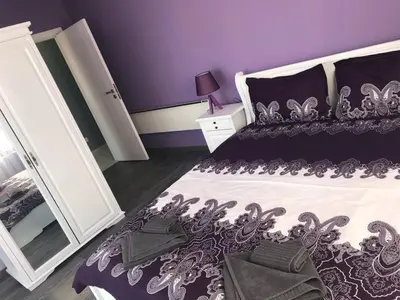 a purple bedroom with a bed and a mirror at Predela 1 Bansko Apartment in Bansko