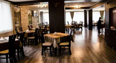 a restaurant with tables and chairs and a person standing in a room at Rubis Hotel in Rudozem