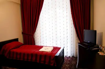 a room with a bed and a window with red curtains at Rubis Hotel in Rudozem