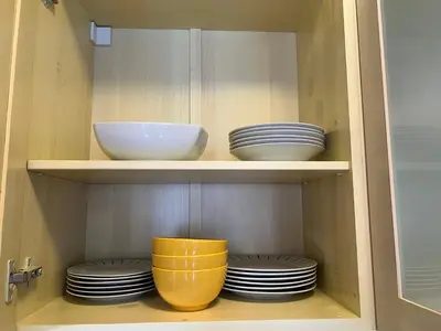 a cupboard with plates and bowls in it at Apartment Saint Ivan Ski Resort in Bansko