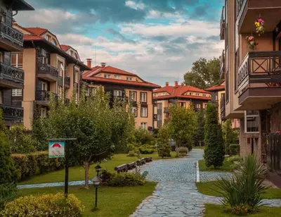 a walkway through a park with buildings and trees at Bojurland Apartment, Bansko in Bansko