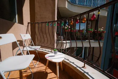 a balcony with white chairs and potted plants on it at Sofia Centre with Free on-site Parking in Sofia
