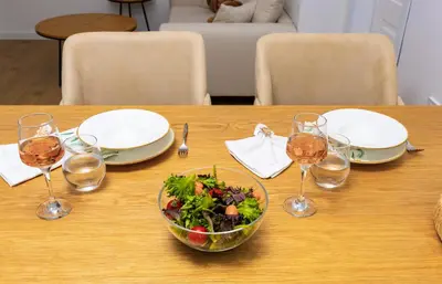 a wooden table with a bowl of salad and wine glasses at Happy People Plovdiv 1-BD Apartment - White by Flat Mаnager in Plovdiv