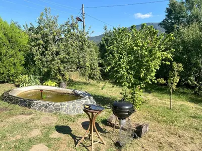 a grill and a smoker in a yard with trees at Cozy Quiet Retreat 70km from Sofia in Kyustendil