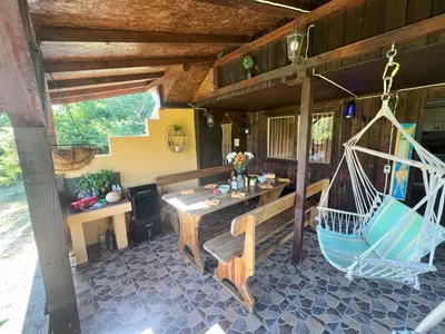 a porch of a house with a swing and a table at Cozy Quiet Retreat 70km from Sofia in Kyustendil