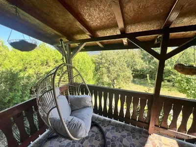 a swinging chair on a porch with a view at Cozy Quiet Retreat 70km from Sofia in Kyustendil