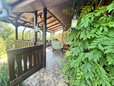 a covered porch with a bench and plants at Cozy Quiet Retreat 70km from Sofia in Kyustendil