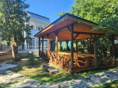 a wooden pavilion with a bench in a park at Вила Княжеска баня in Sofia