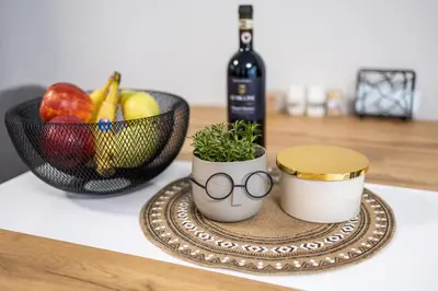 a table with a bowl of fruit and a bottle of wine at Cozy 1BR in Heart of Oborishte with Private Parking in Sofia