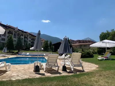 a group of chairs and umbrellas next to a pool at Bansko Royal Towers APARTMENT 738 in Bansko