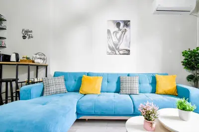 a blue couch in a living room with yellow pillows at 2BR Downtown Suit Next to Nevski Cathedral - AC in Sofia