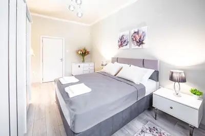 a white bedroom with a large bed and a window at 2BR Downtown Suit Next to Nevski Cathedral - AC in Sofia