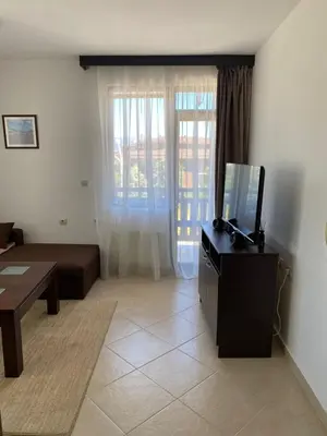 a living room with a tv and a couch and a table at Hill Top Studio Apartments in Bansko