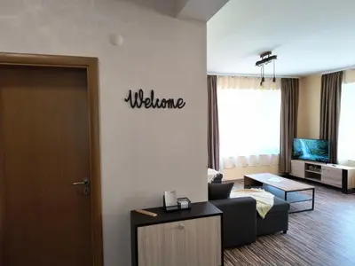 a living room with a welcome sign on the wall at Апартамент за гости Александър in Chepelare