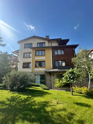 a large building with a grass yard in front of it at Pirin Golf Mountain View Apartment in Razlog