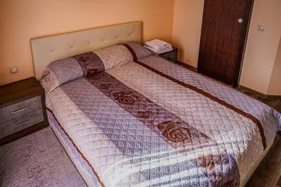 a bedroom with a large bed with a wooden headboard at Апартамент Пирин Apartment Pirin in Sandanski