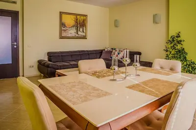a dining room with a table and a couch at Апартамент Пирин Apartment Pirin in Sandanski