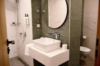 a bathroom with a sink and a mirror and a toilet at B1 Downtown Hotel, Sofia in Sofia