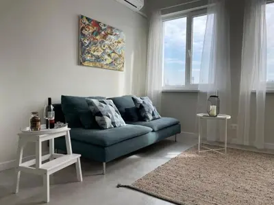 a living room with a blue couch and two tables at Borisova Garden Skyline by Cosher in Sofia