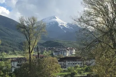a snow capped mountain in the distance with a city at Ruhig in den Bergen Bulgariens in Bansko