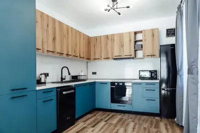 a kitchen with blue cabinets and a black refrigerator at Къщи за гости 