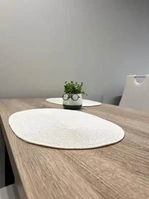 a white plate on a wooden table with a plant at goHOME Plovdiv-apartments and studio in Plovdiv