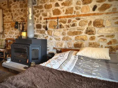 a bed in a stone room with a stove at Books Houses in Beden