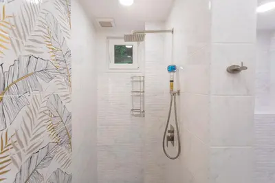 a white bathroom with a shower with a shower at Central St Vitosha Apartment in Sofia