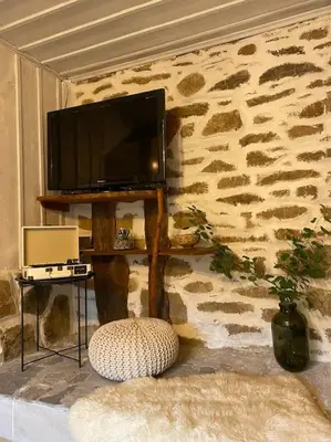 a living room with a television on a stone wall at Beautiful Villa in the Rodopi Mountains in Narechen