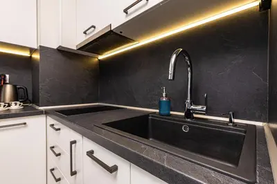 a kitchen with a black sink and white cabinets at Bright and Cozy 1BD Flat in Plovdiv with Parking by Flat Mаnager in Plovdiv