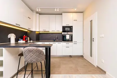 a kitchen with white cabinets and a bar stool at Bright and Cozy 1BD Flat in Plovdiv with Parking by Flat Mаnager in Plovdiv