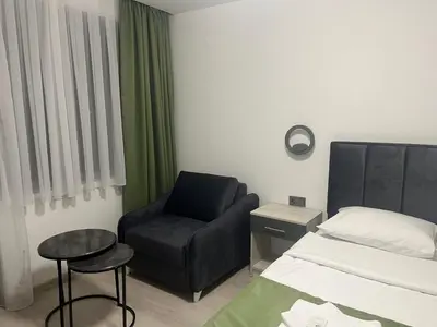 a small bedroom with a bed and a chair at Хотел Лилия in Rudozem